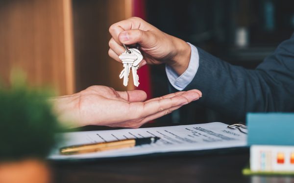 estate agent giving house keys to woman and sign agreement in office