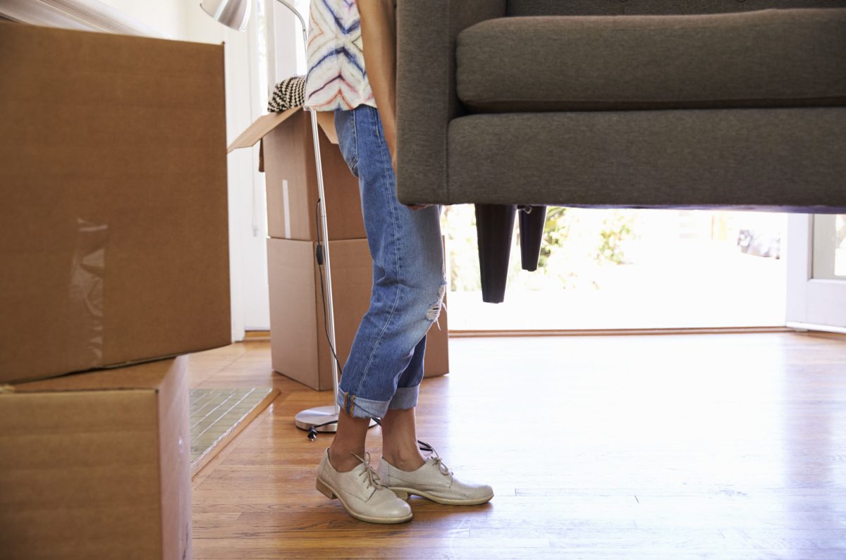 Close up of woman carrying sofa into new home on moving day
